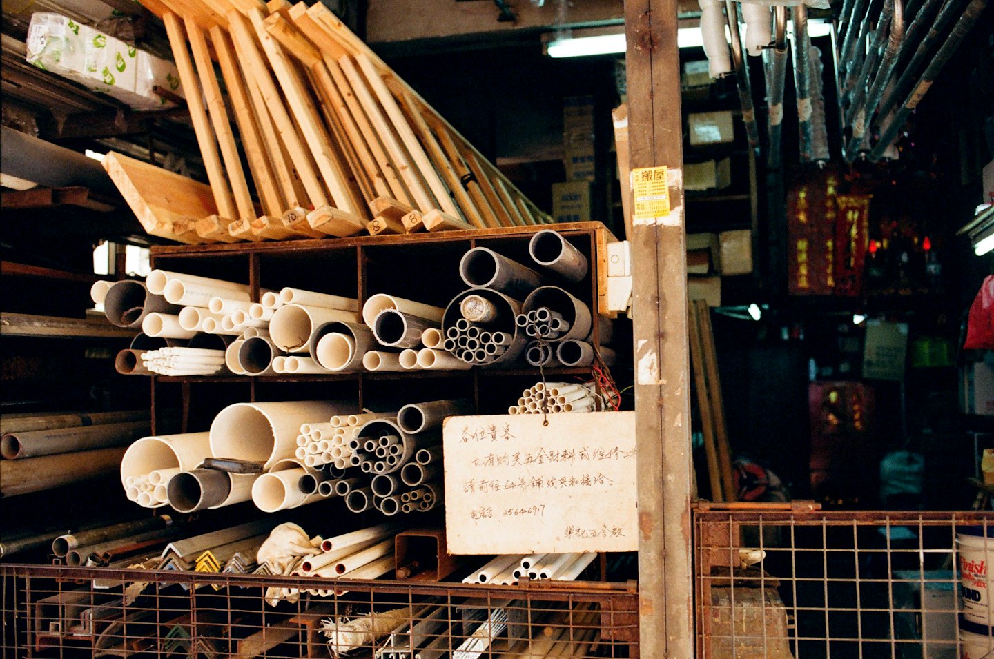 Estanterías de ferretería repletas de tuberías metálicas y tablones de madera.