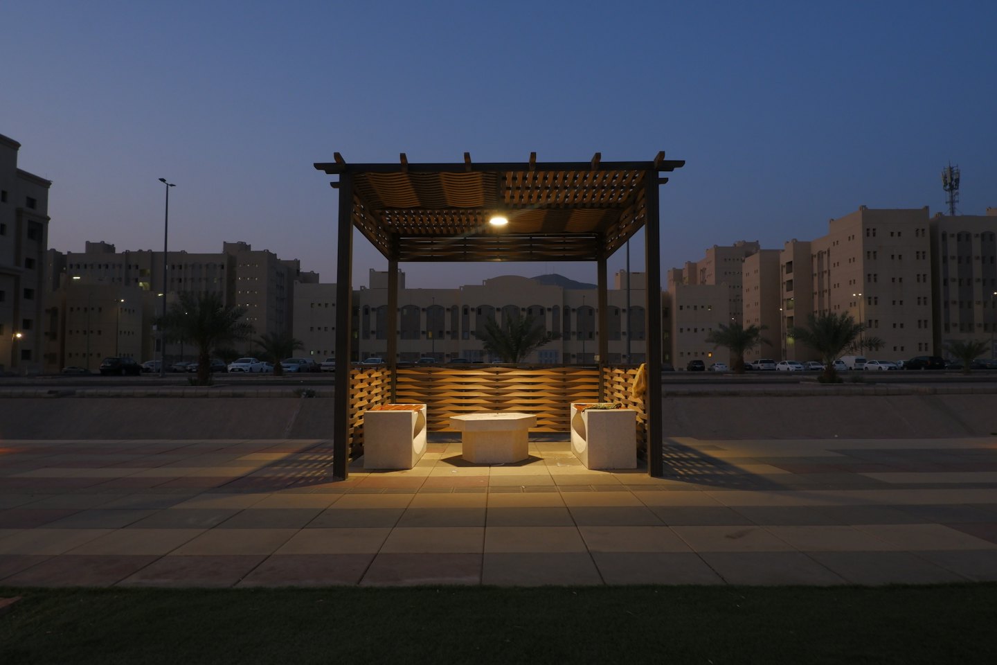 Pérgola moderna de madera con muebles de hormigón en un patio.