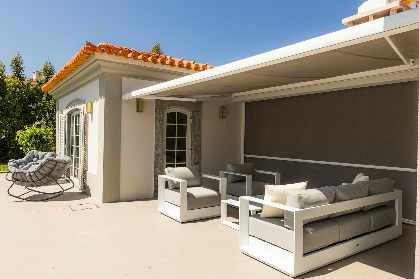 Muebles modernos de salón en un patio con una mecedora.