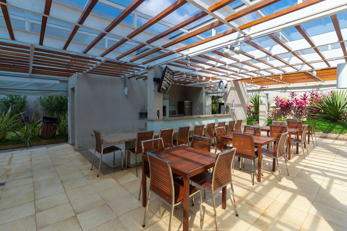 Terraza exterior con mesas, sillas y zona de barbacoa.