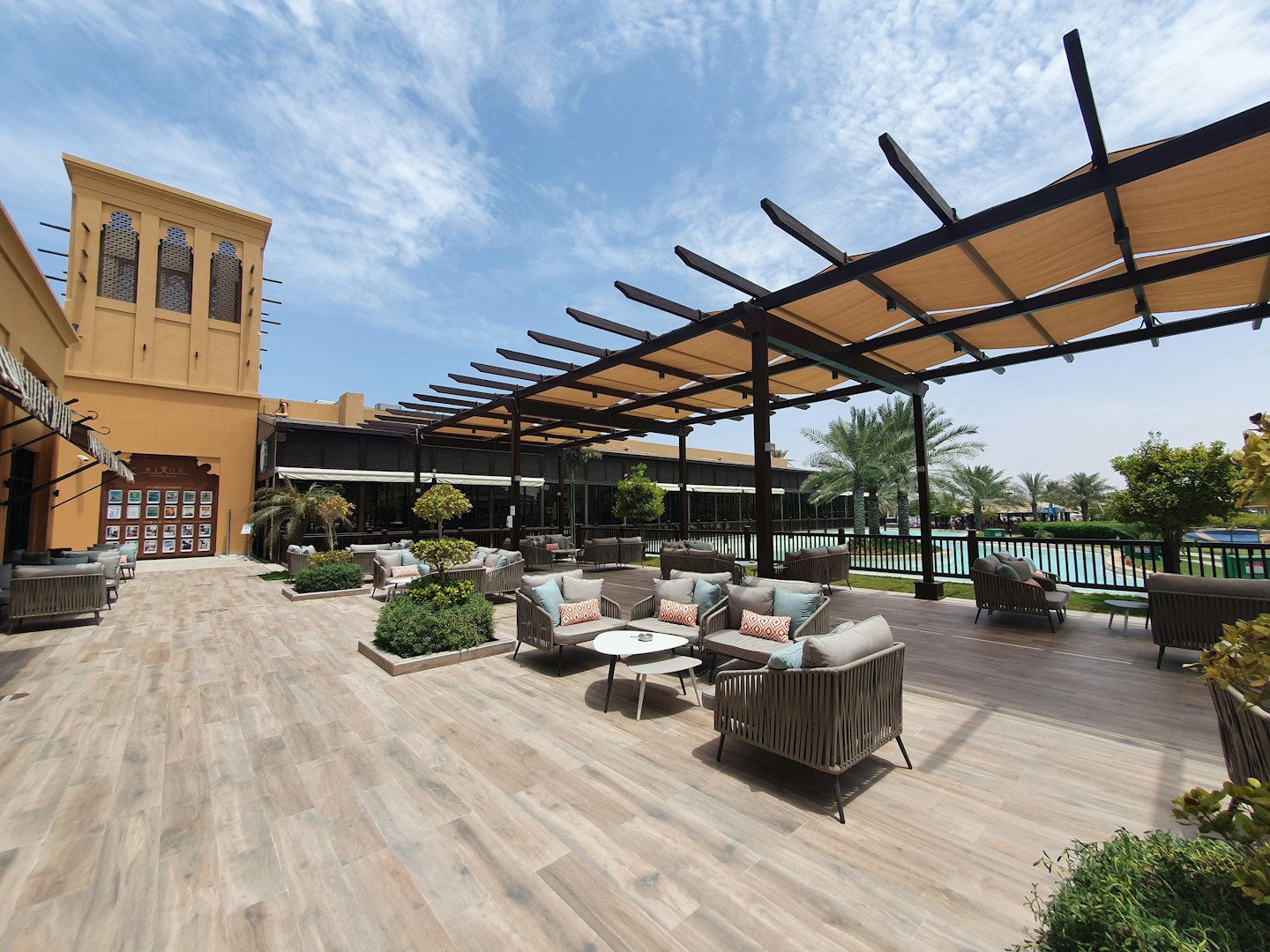 Mobiliario de salón bajo una pérgola cerca de una piscina exterior.