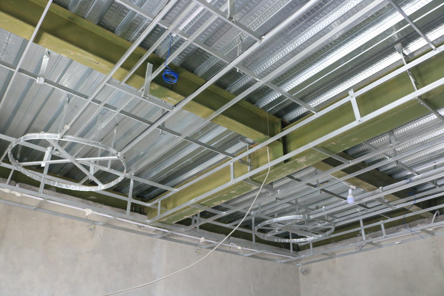 Estructura metálica de techo expuesta con paneles de aislamiento verde claro en construcción.