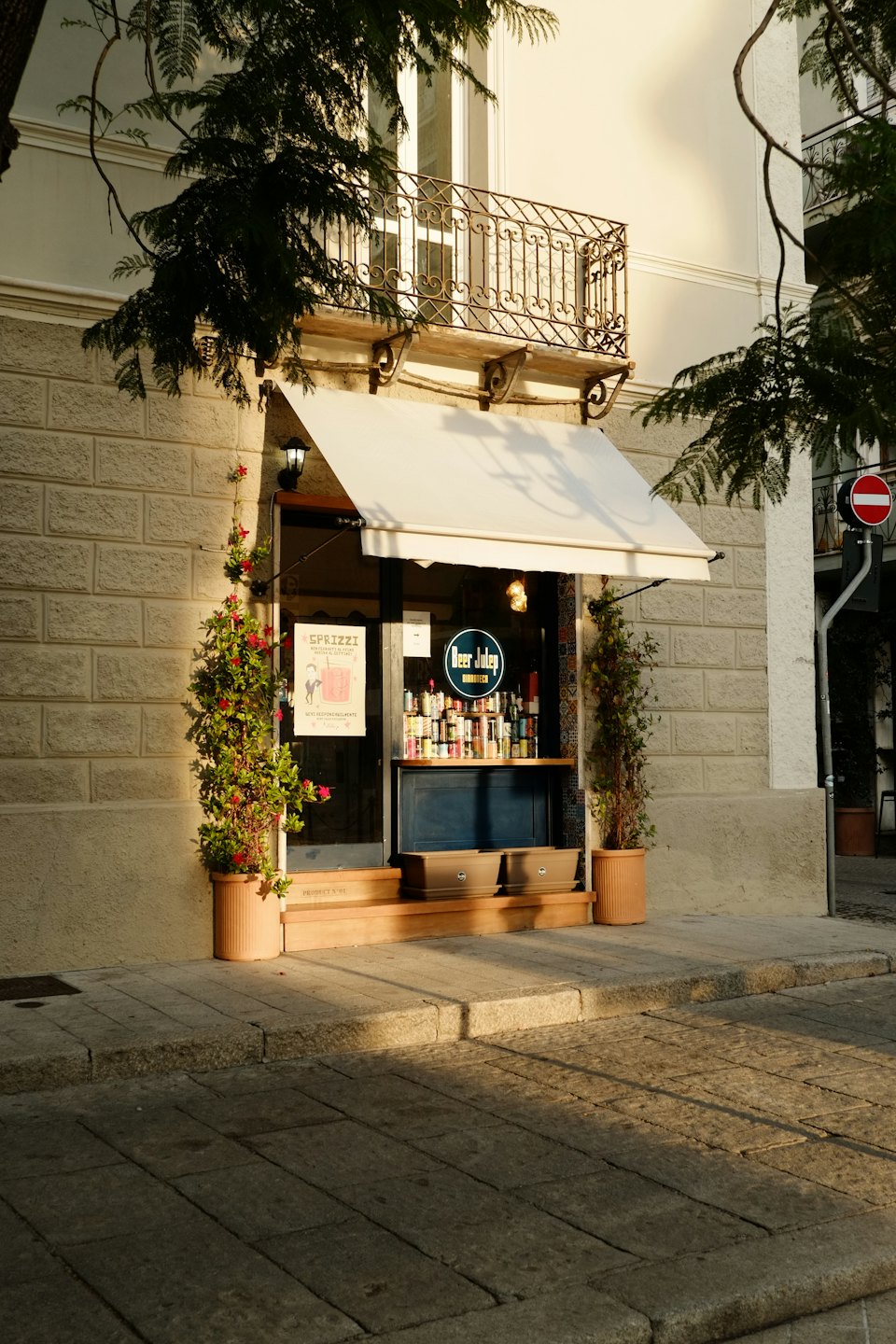 Tienda con toldo blanco y botellas en exhibición.