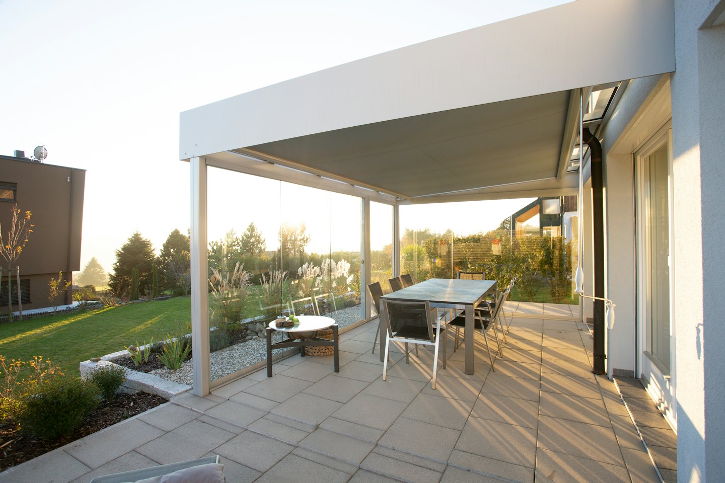 Terraza exterior con pérgola, mesa de comedor y jardín paisajístico.